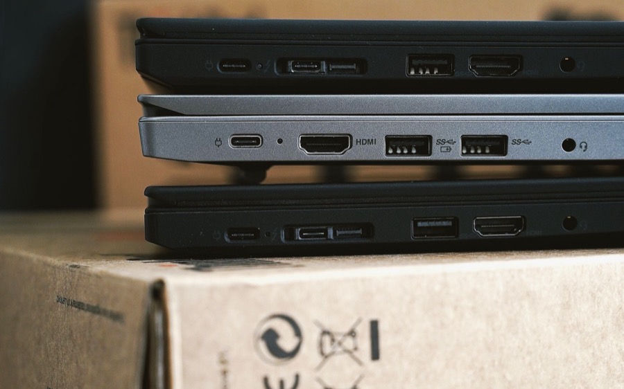 Tres laptops corporativas apiladas sobre sus cajas, listas para inventariarse
