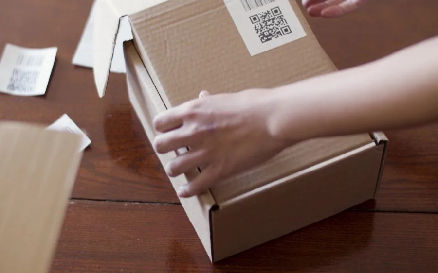 Manos cerrando una caja de cartón lista para enviar